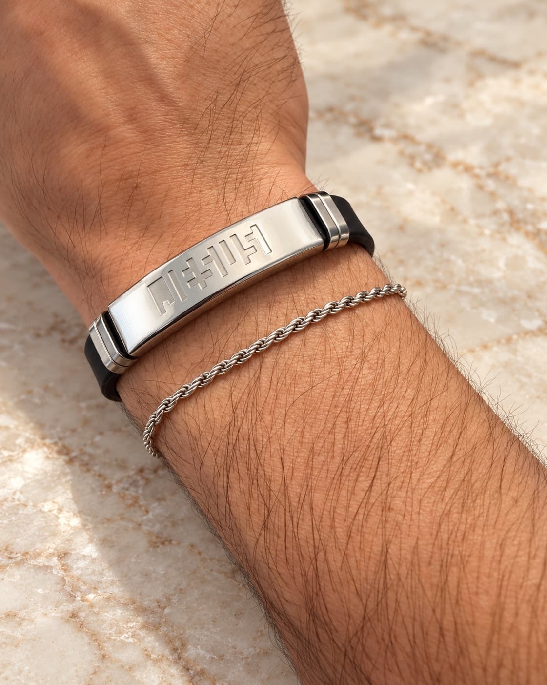 Silver bracelet worn on the wrist alongside a silver chain